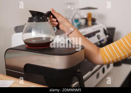 Ein kurzer Schuss einer Barista mit frisch gebrühtem Schwarz Kaffee in einer Glaskanne Stockfoto
