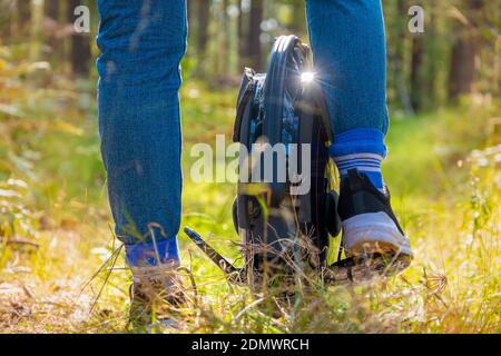 Rückansicht der Frauenbeine auf einem Elektro-Einrad in Der Wald an einem sonnigen Tag Stockfoto