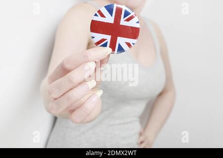 Die Flagge von Großbritannien, allgemein bekannt als Union Jack auf Knopf Abzeichen gedruckt, hält von Frau in ihrer schönen Hand. Stockfoto