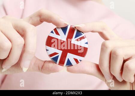 Die Flagge von Großbritannien, allgemein bekannt als Union Jack auf Knopf Abzeichen gedruckt, hält von Frau in ihrer schönen Hand. Stockfoto