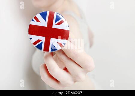 Die Flagge von Großbritannien, allgemein bekannt als Union Jack auf Knopf Abzeichen gedruckt, hält von Frau in ihrer schönen Hand. Stockfoto