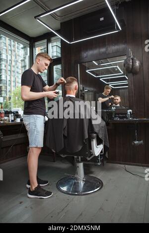 Vertikale Ganzkörperaufnahme eines professionellen Barbiers bei der Arbeit Sein Friseurladen Stockfoto