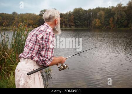 Rückansicht eines älteren Mannes, der auf dem See angeln soll, Kopierraum Stockfoto