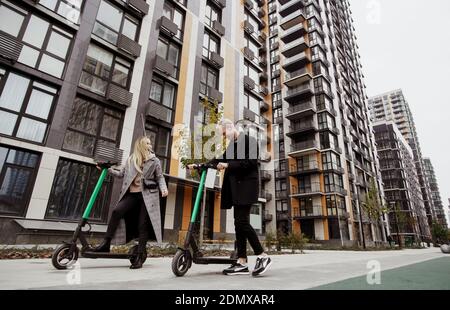 Romantische Datum auf E-Scooter Glückliche Frau mit blonden Haaren und Mann in legerer Kleidung gute Zeit mit dem Fahren auf gemietet Elektro-Scooter und lachen Stockfoto