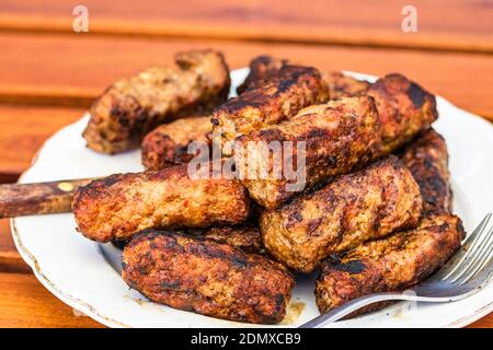 Fleischbrötchen genannt mici oder mititei auf Platte isoliert. Stockfoto