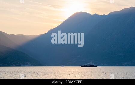 Perast, Kotor, Montenegro. Blick über die Bucht von Kotor, Abend, Sonnenstrahlen werfen dunkle Schatten auf hohe Berglandschaft. Stockfoto