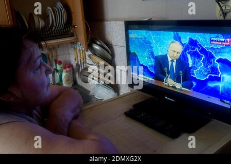 An elderly woman watches the live broadcast of the annual press conference of Russian President Vladimir Putin on TV from her apartment in Tambov.Today Russia is hosting its annual press conference with Russian President Vladimir Putin. This year's conference is held in the video conference mode. The Russian President was broadcasted from his residence in Novo-Ogaryovo. Stock Photo