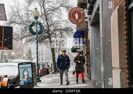 Ein paar Spaziergänge in Richtung Chipotle Mexican Grill Restaurant am Court St.Athens, Ohio bekommt ein bisschen Schnee in der Innenstadt. Stockfoto