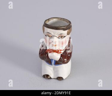 Matchsafe, Porzellan, Figur des Mannes mit Brille. Figur trägt auch kurze braune Mantel und orange Krawatte., wahrscheinlich England, Ende des 19. Jahrhunderts, Container, Dekorative Künste, matchsafe Stockfoto