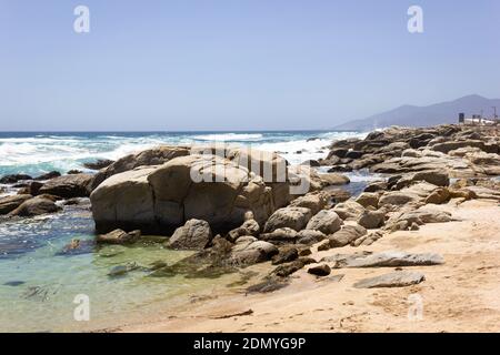 Transparentes Wasser am felsigen Strand an sonnigen Tagen in Maitencillo, Chile. Raues Meer mit wilden Wellen an der Pazifikküste. Sommerzeit, Naturlandschaft Stockfoto