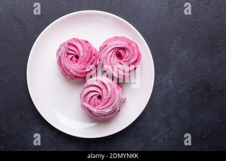 Hausgemachte rosa Marshmallow auf einem schwarzen Stein Hintergrund Draufsicht Weißer Porzellanteller Stockfoto