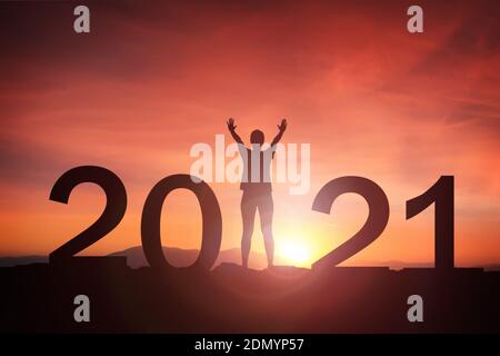 2021 Konzept, 2021 Neujahr Silhouette junge Frau stehend und die Hand nach oben heben Frohes neues Jahr mit Sonnenaufgang, Sonnenuntergang Hintergrund Stockfoto