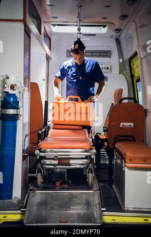 Ein junger Arzt in einer medizinischen Uniform packt seine medizinische Tasche in den Ambulanzwagen. Stockfoto