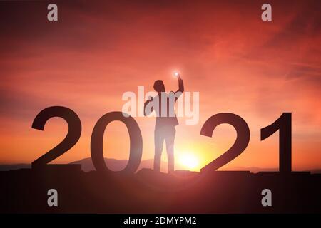 2021 Konzept, 2021 Neujahr Silhouette Young Business Happy Mand stehen und die Hand heben zum Happy New Year mit Sonnenaufgang, Sonnenuntergang Hintergrund Stockfoto