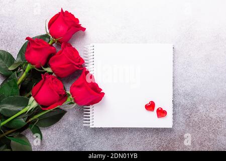 Sketchbook, red rose and decorative hearts on stone background Copy space Top view Valentine's day card - Image Stock Photo