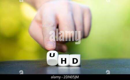 Symbol für einen Ultra High Definition (UHD)-Fernseher. Die Hand dreht Würfel und ändert den Ausdruck „HD“ in „UHD“. Stockfoto