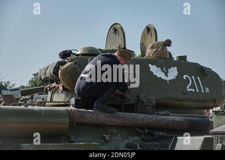 A Russian tank crewman makes doing some maintenance on a World War 2 T34/85 tank at Tankfest 2019 at Bovington Stock Photo
