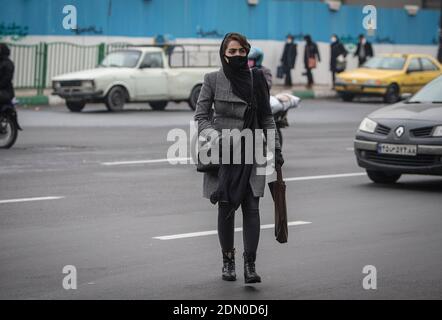 Teheran, Iran. Dezember 2020. Eine Frau mit Gesichtsmaske überquert eine Straße in Teheran, Iran, 16. Dezember 2020. Der Iran berichtete am Donnerstag 7,453 neue COVID-19 Fälle, so dass die Zahl auf 1,138,530 im Land bisher, nach der Website des iranischen Ministeriums für Gesundheit und medizinische Bildung. Quelle: Ahmad Halabisaz/Xinhua/Alamy Live News Stockfoto