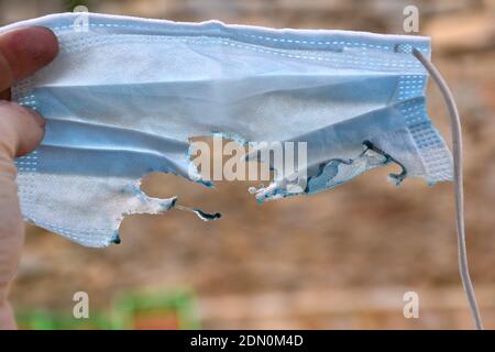 Verbrannte blaue OP-Maske von Hand gehalten. Stockfoto