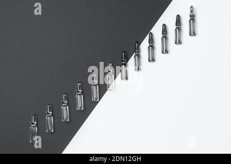 Linie von Ampullen für Injektionen auf trendigen grauen und isolierten weißen Hintergrund. Medizin, Gesundheitswesen und Pharmazie Konzept. Color 2021 Konzept. Flache Lay s Stockfoto