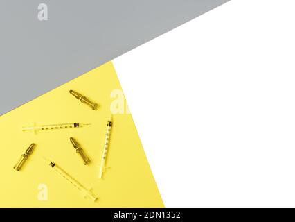Spritzen und Ampullen auf trendigen gelben, grauen und isolierten weißen Hintergrund. Kosmetologie und Medizin Konzept. Color 2021 Konzept. Flache Lay-Optik. Stockfoto