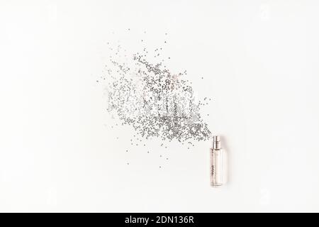 Stilvolle Flasche Parfüm mit Spray von silbernen Stern geformt funkelt auf weißem Hintergrund. Luxus Parfüm Konzept. Kreative trendige flache Lay mit Platz f Stockfoto