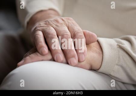 Ältere Männer sitzen allein mit faltigen Händen auf den Knien gefaltet Stockfoto