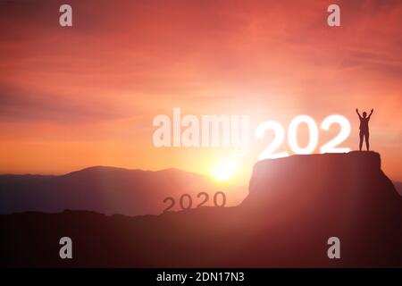 2021 Konzept, Wandern von 2020 bis 2021 Neujahr Silhouette junge Frau stehend und heben die Hand bis zum glücklichen neuen Jahr mit Sonnenaufgang, Sonnenuntergang Hintergrund Stockfoto