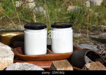 Handgemachte Ziegen- und Kuhmilch-Joghurts auf einem Holztablett und verschiedene Käsesorten. Stockfoto