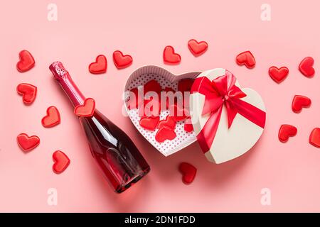 Valentine's Day box in shape of heart and sparkling wine on pink background. View from above. Flat lay. Romantic greeting card. Stockfoto