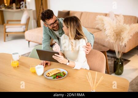 Schönes junges Paar mit digitalen Tablet und mit Frühstück in Die Küche Stockfoto