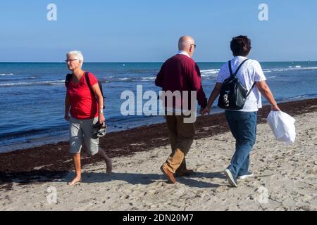 Ältere Paare, die zusammen am Strand spazieren Stockfoto