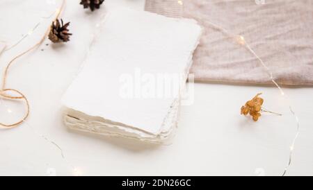 Weihnachtswunsch Konzept. Handgemachtes Papier mit Bastelfaden gebunden. Briefumschlag, Tannenzapfen, Bastelfaden. Hygge-Stil flach Lay, selektiver Fokus Stockfoto
