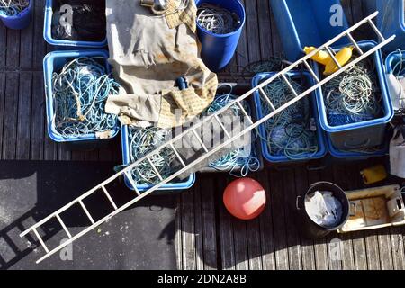 Blick von oben auf die Angelausrüstung mit Leiter und Fischernetzen, die auf einem Holzdock im Hafen organisiert sind Stockfoto