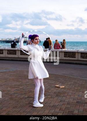Brighton UK 17. Dezember 2020 - AA Hula Hooping Busker unterhält Besucher an der Küste von Brighton am Ende eines hellen Tages an der Südküste . Die Stadt Brighton und Hove wurde in Coronavirus Tier zwei Beschränkungen in England nach einer Ankündigung heute von der Gesundheitsminister Matt Hancock gehalten : Credit Simon Dack / Alamy Live News Stockfoto