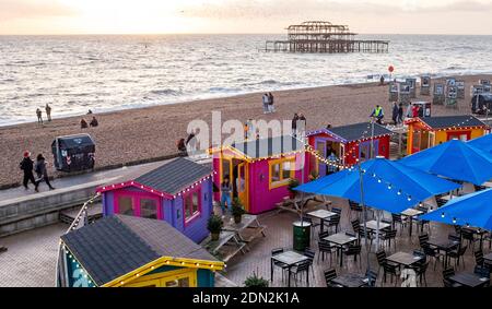 Brighton UK 17. Dezember 2020 - Besucher genießen einen Drink an den Strandhütten, die von einer Strandbar der Brighton Music Hall am Ende eines hellen Tages an der Südküste eingerichtet wurden. Die Stadt Brighton und Hove wurde in Coronavirus Tier zwei Beschränkungen in England nach einer Ankündigung heute von der Gesundheitsminister Matt Hancock gehalten : Credit Simon Dack / Alamy Live News Stockfoto