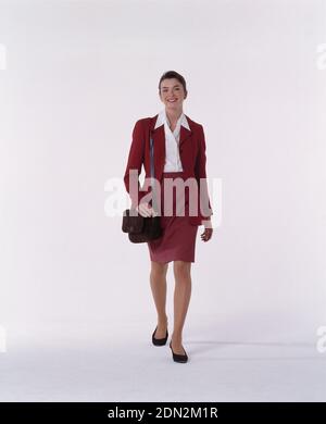 In voller Länge Vorderansicht der jungen Frau in rotem Anzug. Stockfoto