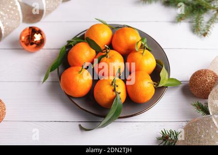 weihnachtsmandarinen in Teller auf weißem Holztisch Stockfoto