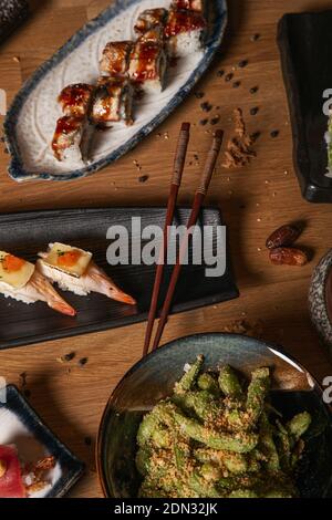 Auswahl an japanischem Sushi, Nigiri, Wakame-Salat in Keramikplatten mit Sojasauce auf Holztisch. Kopierbereich Japanisches Menü. Stockfoto