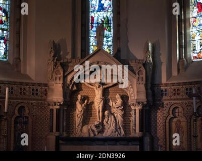 Steinreredos mit Kreuzigung Szene unterhalb der Edikula im östlichen Ende Apsidal der Holy Trinity Church, Dilton Marsh, Wiltshire, England, UK. Stockfoto