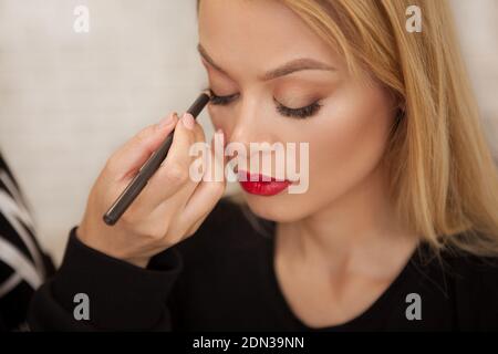 Draufsicht Nahaufnahme eines Make-up-Künstlers mit Kajal Auf die Augen einer schönen Frau Stockfoto