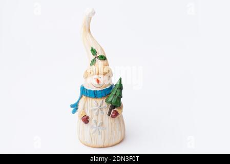 Lustiges Spielzeug Schneemann mit blauem Schal, große weiße lustige Mütze und weihnachtsbaum in der Hand auf weißem Hintergrund mit einem Kopierraum. Stockfoto