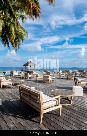Holzplattform mit Blick auf das Meer mit Tischen und Sofas, Restaurant in einem Luxusresort, tropisches Paradies, Malediven. Stockfoto