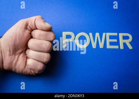 Macht, menschliche Faust neben Wort geschrieben mit Plastikbuchstaben auf blauem Papierhintergrund, Konzept Stockfoto