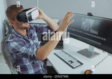 Fröhlicher Mann lächelt, versucht 3D vr Brille, eine Pause von der Arbeit online. Glücklicher Mann, der sich zu Hause entspannt, mit einer Virtual-Reality-Brille Stockfoto