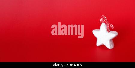 Weihnachtsbanner mit flauschiger weißer Sterndeko auf rotem Hintergrund. Winterurlaub Ornamente. Minimalistische Komposition. Stockfoto