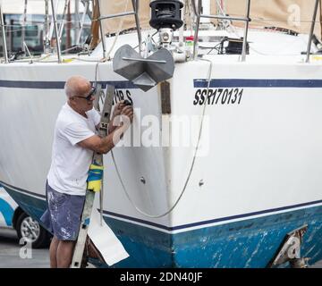 Mann, der Registrationsnummern auf der Yacht im Bootshof einlegt. Stockfoto