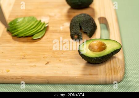 A closeup of sliced avocados on a wooden table on the table Stockfoto