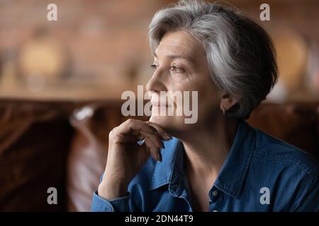 Nachdenkliche ältere 70er Jahre Frau, die in der Ferne sucht. Stockfoto