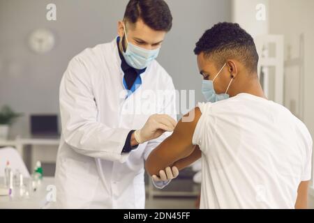 Doctor cleans skin on patient's arm with disinfectant before injecting him with vaccine Stock Photo